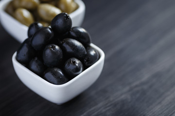 Olives in a white bowl on a dark wooden table