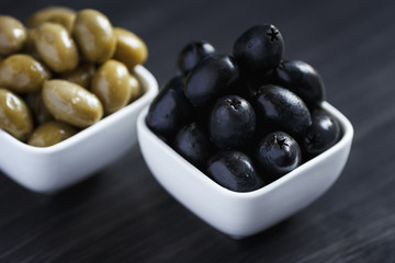 Olives in a white bowl on a dark wooden table