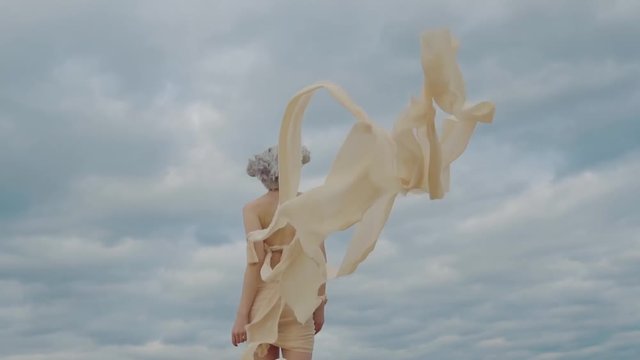 Extravagant blond girl is strolling, wearing ropes on her naked body. Back view of her, woman is turning and stretching hands to camera