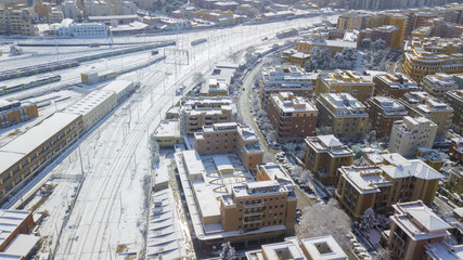 Fototapeta premium Aerial view of the Tuscolana station in Rome, Italy. Around the tracks there are the palaces and streets of the Italian city. The railroad tracks are made of steel. Everything is covered by snow on 02