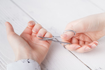 beauty salon, manicure applying, cutting the cuticle with scissors