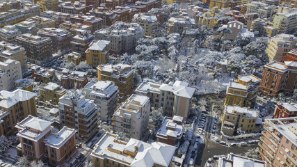 Aerial view of a group of buildings in the Tuscolana district in Rome, Italy. The buildings and streets are unusually covered with snow and ice. The roofs are passable and with antennas and TV dishes.