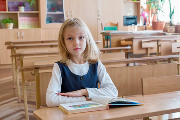 girl in the first grade, is sitting at the desk with book