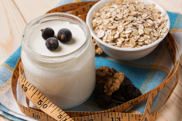 yogurt in a jar, oat flakes and nuts, a measuring tape, the concept of a healthy diet