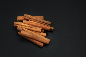 Bundle of cinnamon sticks on black background.