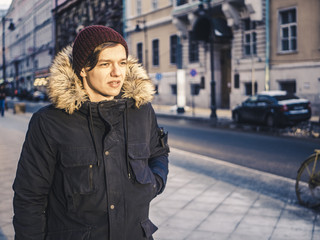 Obraz premium adult long hair man in jacket walking in the europe street on a winter day