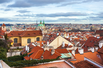 Fototapeta premium View of Prague over houses with red roofs. Amazing view from above at old historical quarter. Prague, Czech Republic. Prague is famous and popular travel destination city