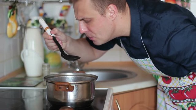 A guy trying a dish on the palate while cooking, he will make a grimace of tastelessness