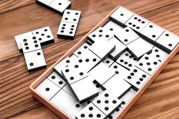 Box with domino pieces on wooden table.