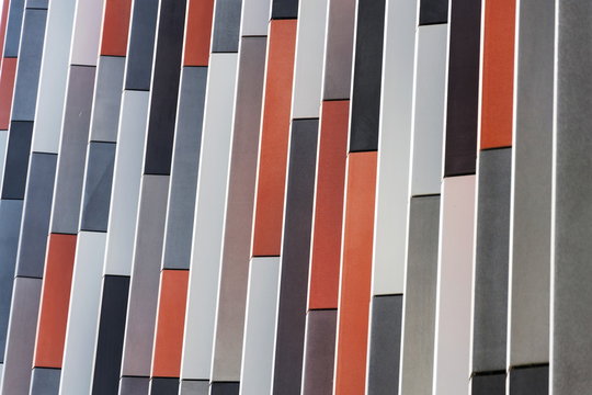 Orange, grey and white brise soleil sun breakers on modern office building on sunny day