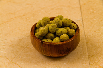 Bowl of wasabi covered peanuts.