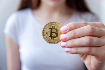 Cryptocurrency golden bitcoin coin in woman hand. Electronic virtual money for web banking and...