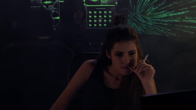 Two hackers working in darkness and smoke closeup
