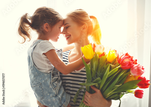 happy mother's day! child daughter   gives mother a bouquet of flowers to tulips.
