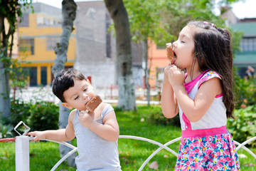 Latin kids eating ice-cream in the summer park.
