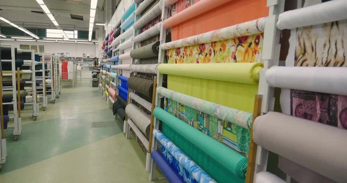 In a textile shop, there are fabrics of various colors and various materials, such as fabric, lace, satin, linen. Concept of: tailoring, colors, fabrics, clothes and fashion.