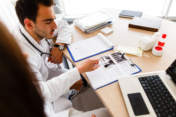 Young male doctor looking at paperboard