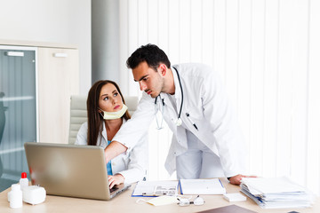 Beautiful nurse and young doctor work on laptop