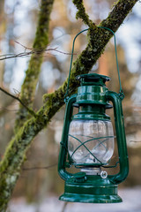 Oil lamp suspended on a branch in the forest. Old traditional lighting by the forest path.