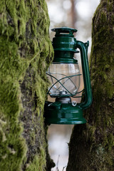 Oil lamp suspended on a branch in the forest. Old traditional lighting by the forest path.