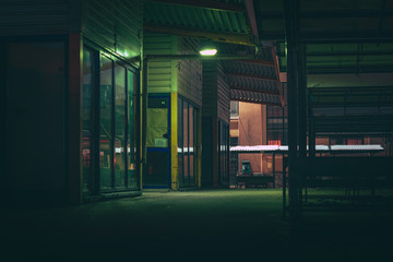 Central marketplace at night time. Isolated territory filled with trading stands and lighten by city lights. Spooky and abandoned atmosphere in urban market territory.  - obrazy, fototapety, plakaty