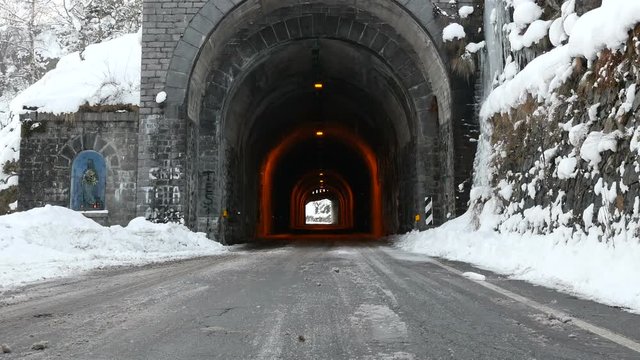 Road with ancient stone tunnel in winter scenic with icicles and snow, Bielmonte, Italy