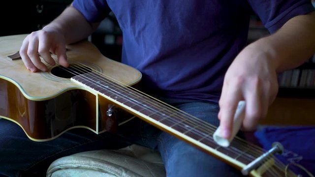 Closeup of a musician playing a slide guitar with a pvc section of pipe.
