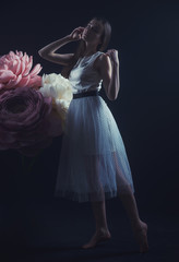 girl in a light dress among the huge flowers made of paper and formina