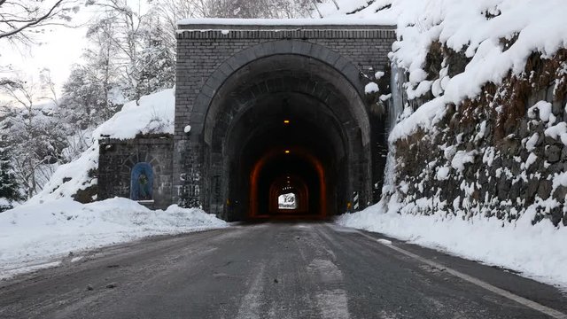Road with ancient stone tunnel in winter scenic with icicles and snow, Bielmonte, Italy