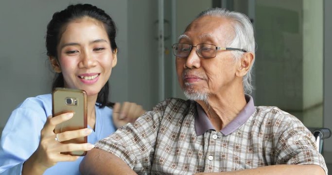 Young Asian female and elderly man taking selfie photo together at home. Shot in 4k resolution