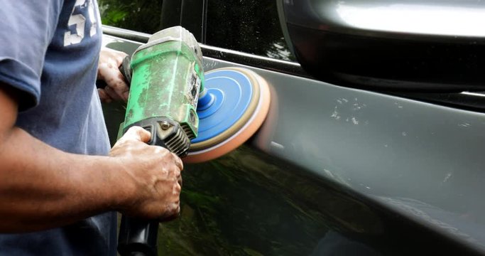 JAKARTA - Indonesia. February 28, 2018: Male auto mechanic worker using a polishing machine to polish the car body. Shot in 4k resolution