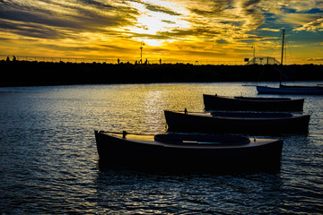 Fototapeta premium Small boats in silhouette are anchored at St Kilda Marina in front of the penguin scantuary in Melbourne Australia