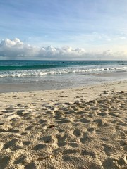 Idyllic and beautiful afternoon at the beach in Barbados (Caribbean island): Nobody, white sand, clear turquoise water with waves and a sunny blue sky white clouds