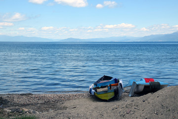 Boat and pedalo on Ohrid lake beach. Podgradec, Albania.
