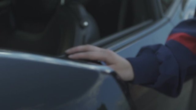 A female hand touches the door and rear mirior of a black sports car in slow motion