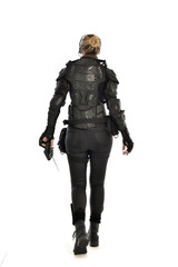 full length portrait of female  soldier wearing black  tactical armour, holding a remote control, isolated on white studio background.