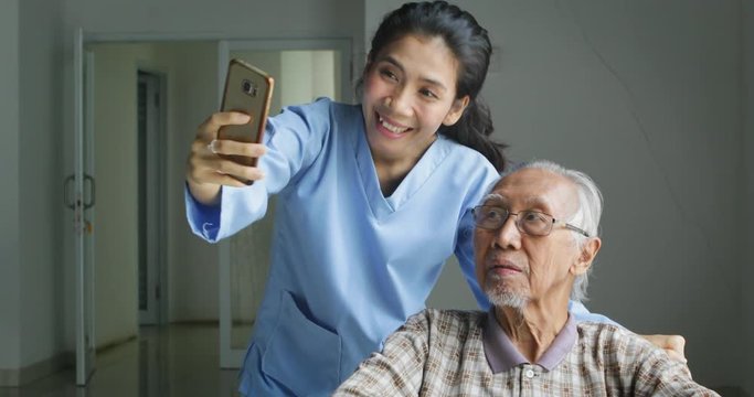 Female nurse and elderly man taking selfie photo together with a mobile phone in the hospital. Shot in 4k resolution