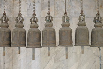 Obraz premium Row of big bells hanging in the Buddhism temple with the marble tiles in the background