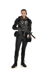 full length portrait of female  soldier wearing black  tactical armour, holding a rifle gun, isolated on white studio background.