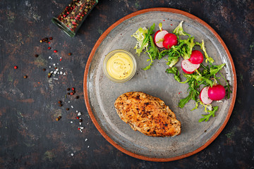 Baked chicken breast and fresh vegetables on the plate on a dark background. Proper nutrition. Dietary menu. Flat lay. Top view