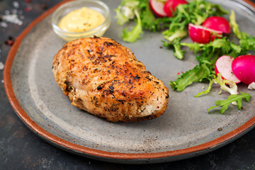 Baked chicken breast and fresh vegetables on the plate on a dark background. Proper nutrition. Dietary menu.