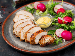 Baked chicken breast and fresh vegetables on the plate on a dark background. Proper nutrition. Dietary menu.