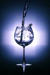 Close up  colored water splash in wine glass, pouring water into glass.