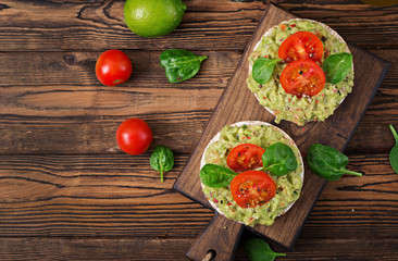Healthy breakfast. Sandwich crisp bread with guacamole and tomatoes on a wooden background.