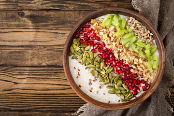 Delicious and healthy oatmeal with kiwi, pomegranate and seeds. Healthy breakfast. Fitness food. Proper nutrition. Rustic style. Flat lay. Top view