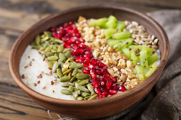 Delicious and healthy oatmeal with kiwi, pomegranate and seeds. Healthy breakfast. Fitness food. Proper nutrition. Rustic style