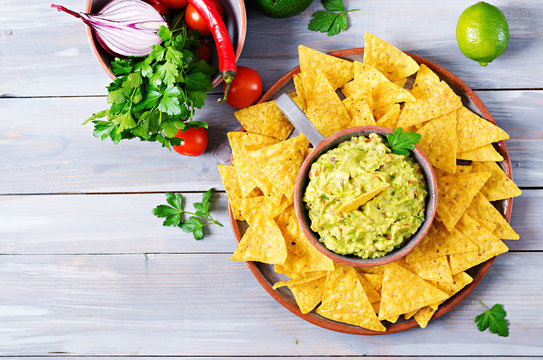 Guacamole avocado, lime, tomato, onion and cilantro, served with nachos - Traditional Mexican snack. Flat lay. Top view.