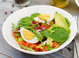 Delicious and light salad of tomatoes, eggs and a mix of lettuce leaves. Healthy breakfast.