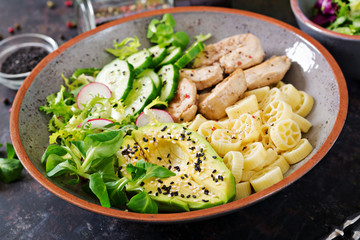 Healthy salad with chicken, avocado, cucumber, lettuce, radish  and pasta on dark background. Proper nutrition. Dietary menu. Dinner.