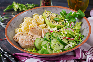 Healthy salad with chicken, avocado, cucumber, lettuce, radish  and pasta on dark background. Proper nutrition. Dietary menu. Dinner.